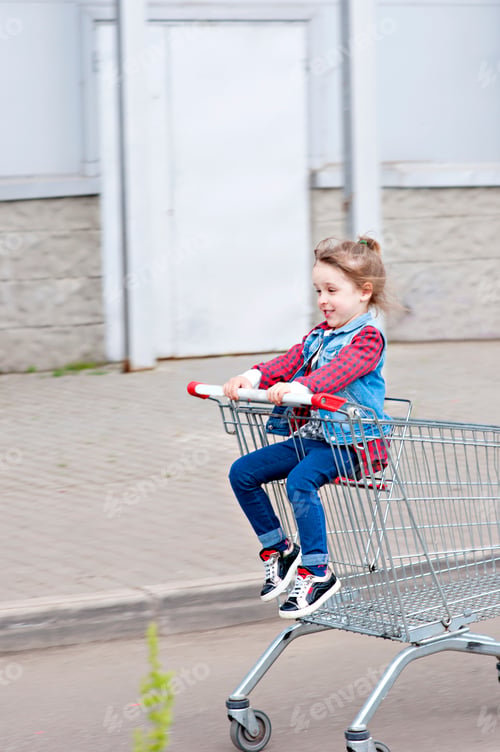Preview: Little girl has fun while sitting in shopping trolley. The child went shopping with parents