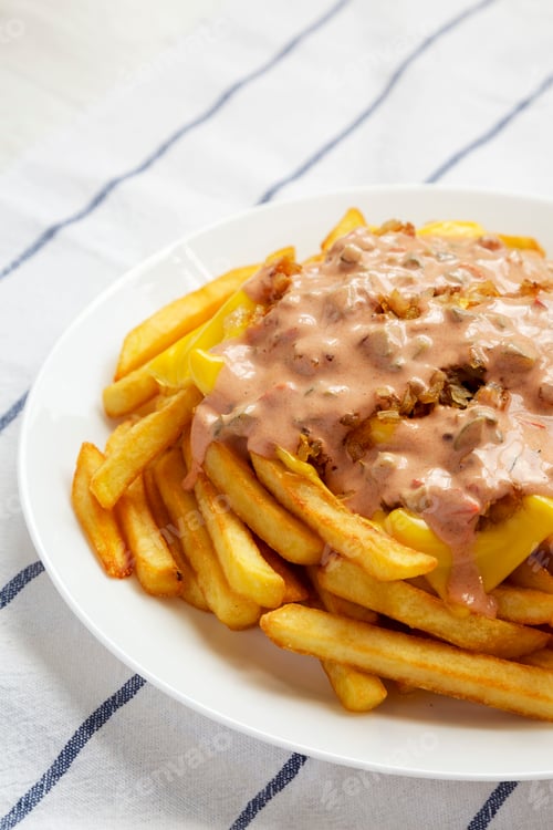 Preview: Homemade Animal Style French Fries on a white plate, side view.