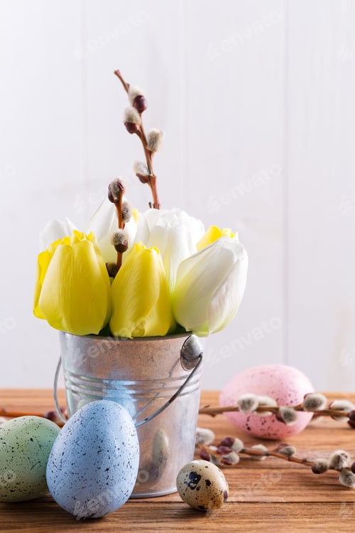 Preview: Happy Easter card with fresh spring tulips flowers in a bucket and handmade painted eggs on a wooden