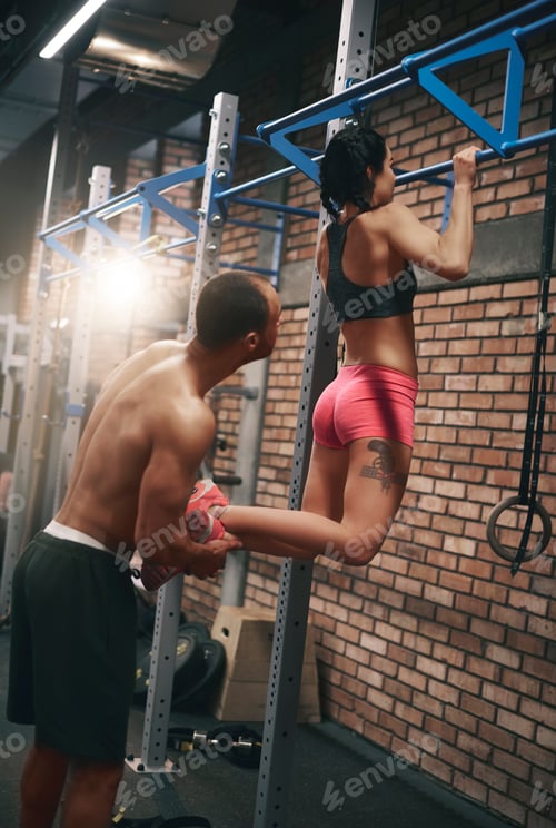 Preview: Personal trainer helping woman with pull ups