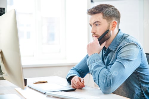 Preview: Pensive male designer thinking and making blueprints using pen tablet