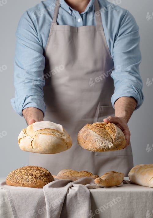 Preview: Baker in a denim shirt holds out bread