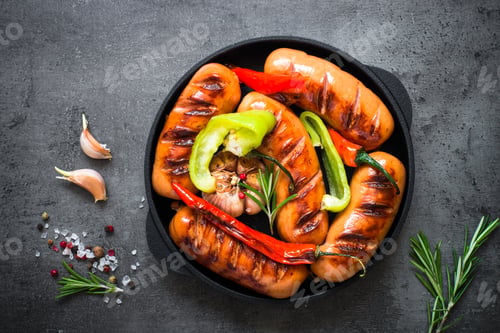 Preview: Fried bbq sausages with vegetables at black slate table.