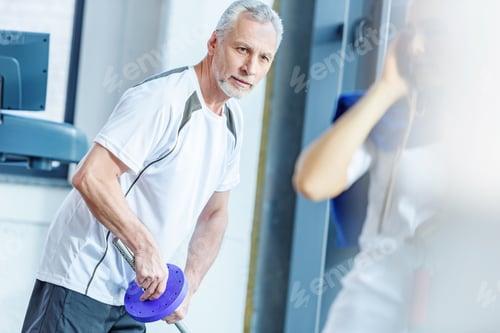 Preview: Bearded mature man in sportswear holding barbell in gym