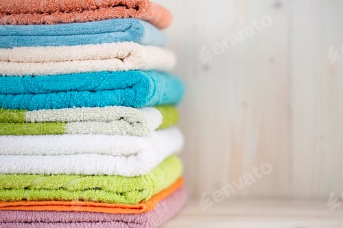 Preview: A stack of clean multi-colored towels on a wooden surface.