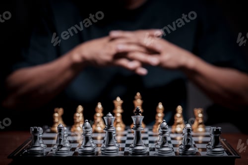 Preview: Business man with clapped hands planning a strategy with chess figures on chessboard