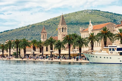 Preview: Coastal town of Trogir with palm trees, historic stone buildings, and a yacht anchored