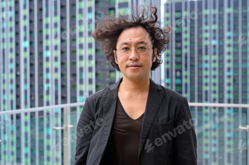 Preview: Japanese businessman with curly hair wearing suit against view of the city