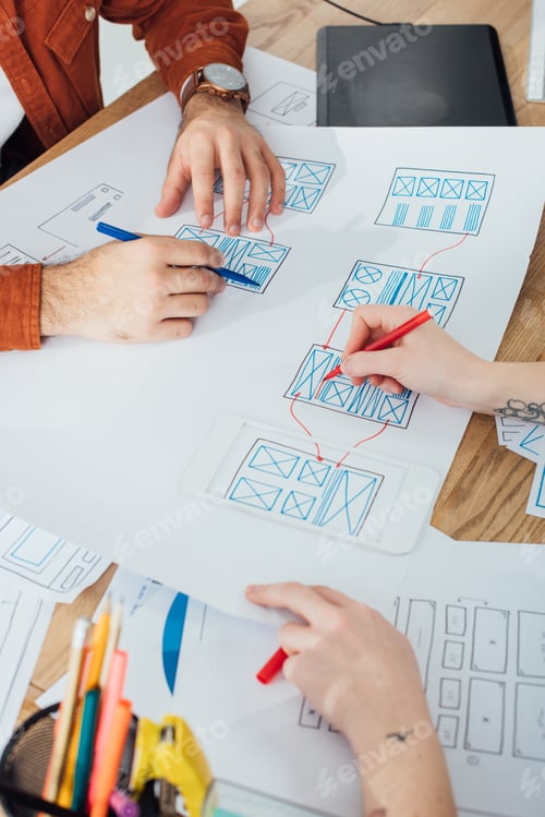 Preview: Cropped view of ux designers working with layouts and sketches on table
