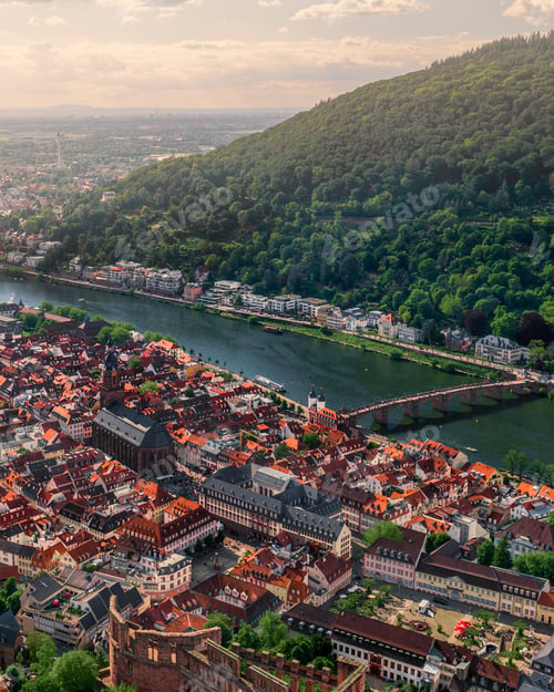 Preview: Vertical shot of cityscape and hill with forests and a river on a sunny day