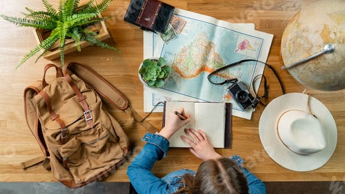 Preview: Top view of young woman with maps planning vacation trip holiday, desktop travel concept.