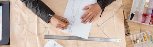 Preview: Top view of african american designer drawing sketch on sewing print in workshop, banner