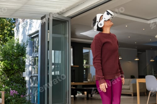 Preview: African American woman wearing white VR headset and maroon sweater standing in doorway to garden