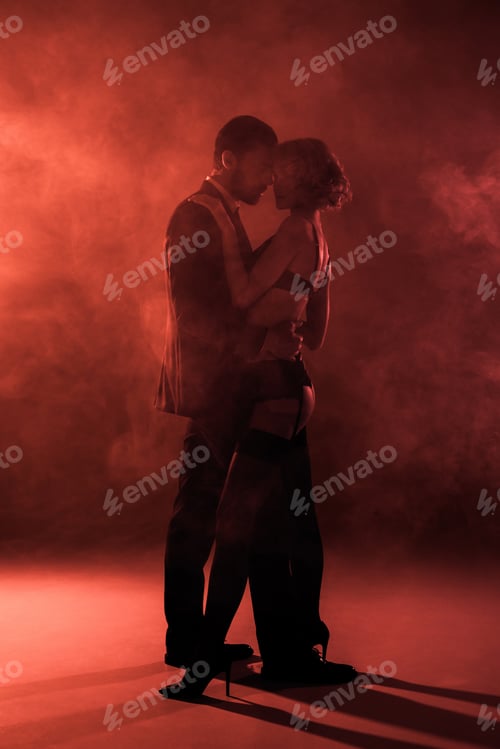 Preview: Beautiful couple hugging and almost kissing on red smoke background
