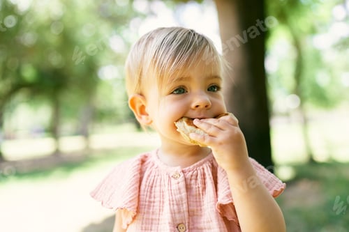 Preview: Little girl eats pancake on a green lawn