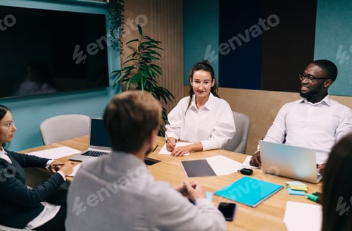 Preview: Cheerful colleagues discussing business ideas in boardroom