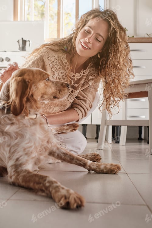 Vista previa: Mujer sonriente acariciando a Spaniel en la cocina