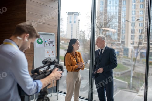 Preview: Young asian reporter having a conversation with a grey-haired man