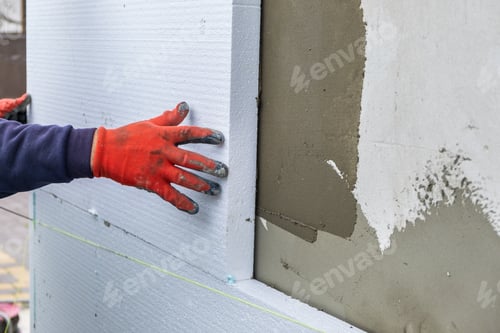 Preview: Construction worker installing styrofoam insulation sheets on house facade wall