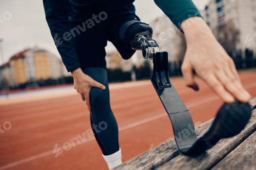 Preview: Close-up of runner with artificial leg warming up at the stadium.