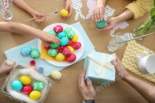 Preview: Family with colorful Easter eggs at table, top view