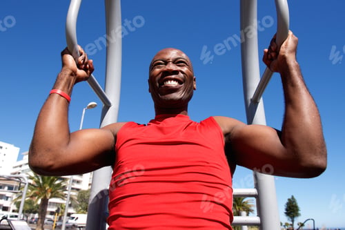 Preview: African man doing pull up exercise workout outdoors