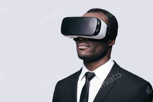 Preview: Another reality is here! Handsome young African man in VR headset standing against grey background