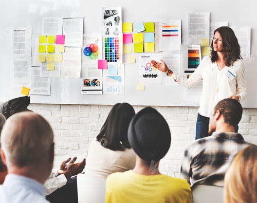 Preview: Audience listening to a woman talk about ideas on the board