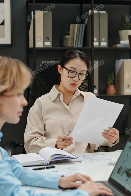Preview: Asian Businesswoman Reading Document at Business Meeting in Office