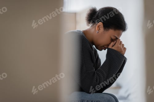 Preview: Side view of multiracial woman with mental problem crying at home