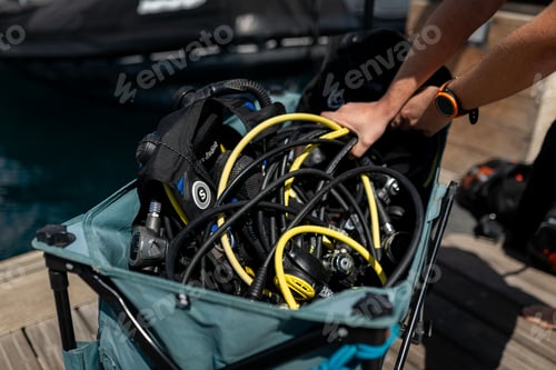 Preview: Divemaster pushing cart full of scuba diving equipment on pier
