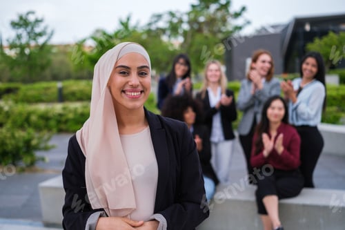 Preview: Young woman with hijab smiles applauded by her co-workers