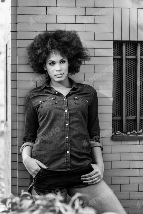 Preview: Young black woman with afro hairstyle standing in urban backgrou