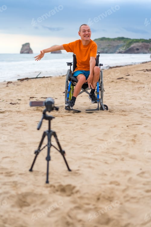 Preview: Portrait of a disabled person in a wheelchair on the beach recording a video for an interview