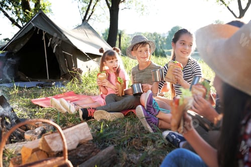 Preview: Little children eating sandwiches near bonfire and tent. Summer camp