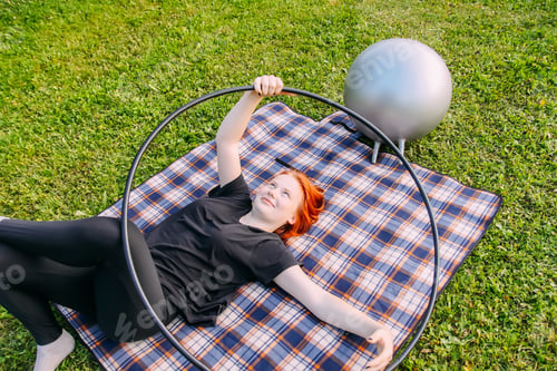 Preview: A teenager girl lying on the checkered plaid with the gymnastic hoop.