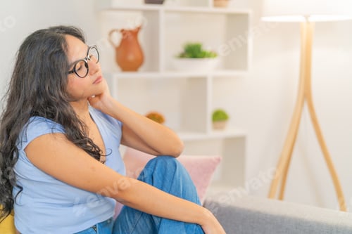 Preview: Thoughtful woman sitting alone in the sofa at home