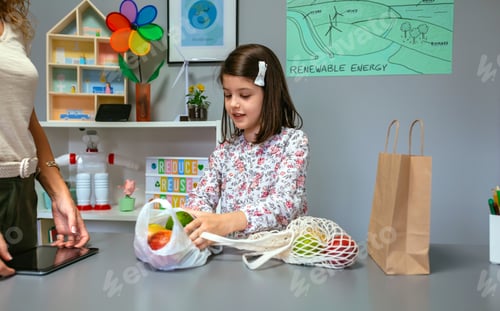 Preview: Student taking fruits from disposable plastic bag to reusable mesh bag in ecology classroom