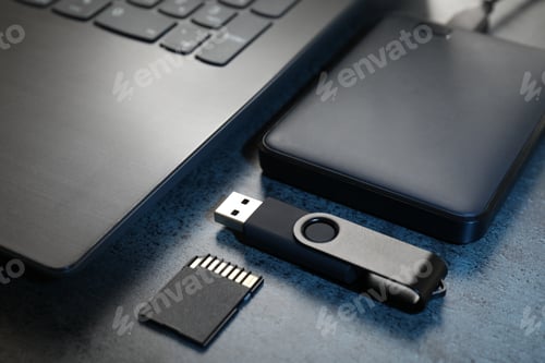 Preview: SD memory card, USB flash drive, hard disk drive and laptop on dark grey table, closeup