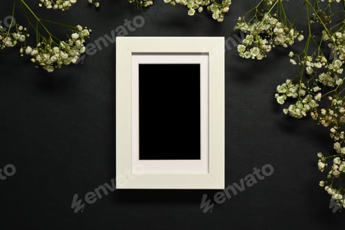 Preview: Empty wooden picture frame with white baby's breath flowers on dark background.