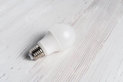 Preview: lightbulb lying on white background and hand holding it b