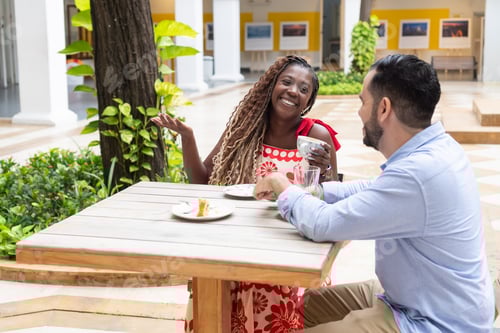 Preview: Happy couple enjoying coffee and conversation at outdoor cafe