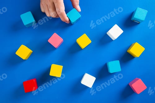 Preview: Businesswoman organizing colorful wooden cubes on blue background