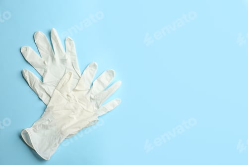 Preview: Pair of medical gloves on light blue background, flat lay. Space for text