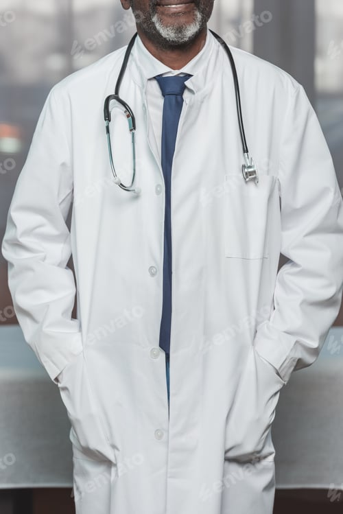 Preview: Doctor in White Coat with Stethoscope Poses Indoors