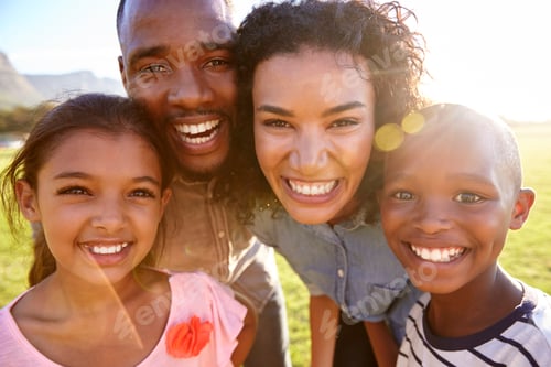 Preview: Laughing black family outdoors, close up, back lit portrait