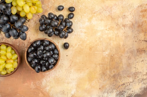 Preview: Half shot of black and yellow fresh grapes in small brown wooden pots in basket and on table on