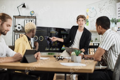 Preview: Group of four partners sitting at desk and listening speech of caucasian man near huge monitor