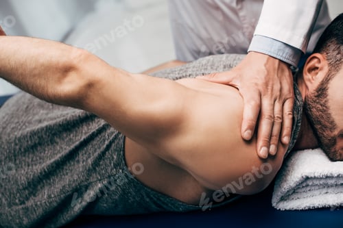 Preview: Physiotherapist stretching arm of patient in hospital