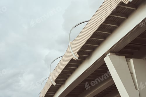 Preview: Part of modern bridge with street led lights against cloudy sky. Engineering construction closeup